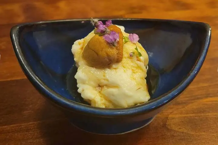 こちらの居酒屋のお通しはウニをのせた自家製のごま豆腐。穂紫蘇（ほじそ）を散らし、盛り付けも美しくこだわっています