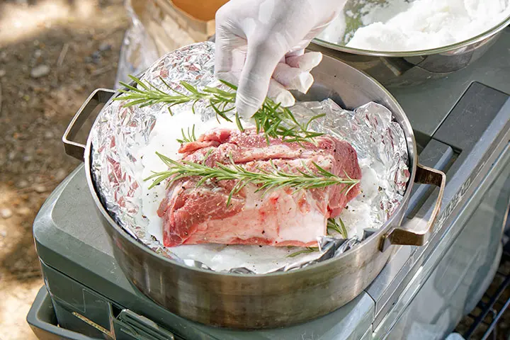 塩の土台の上に豚肉を置き、そのうえにローズマリーをのせる