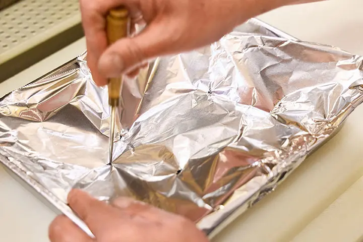 錐でアルミホイルに穴を開ける様子